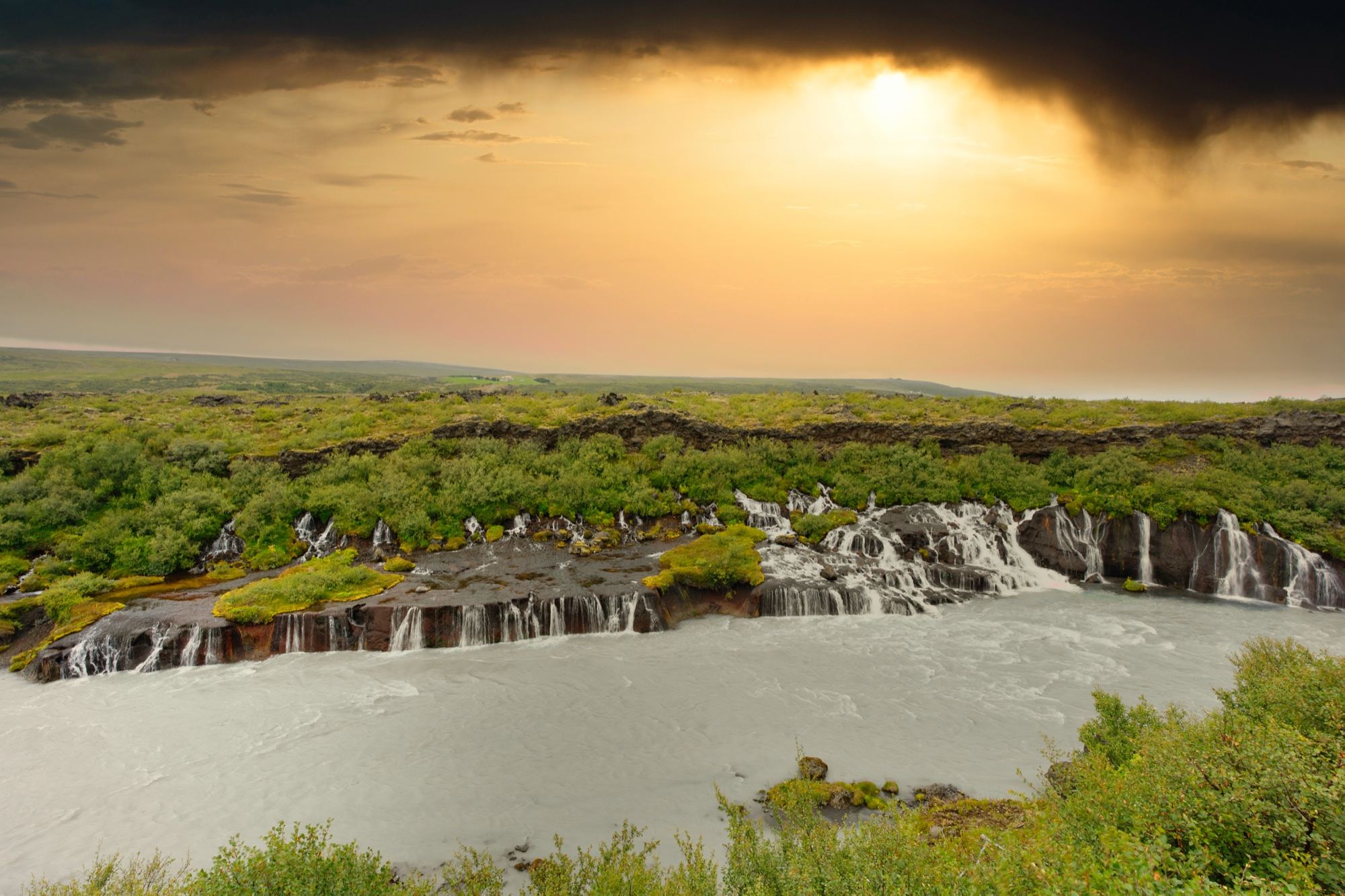 Hraunfossar waterfalls under a gold evening sky
